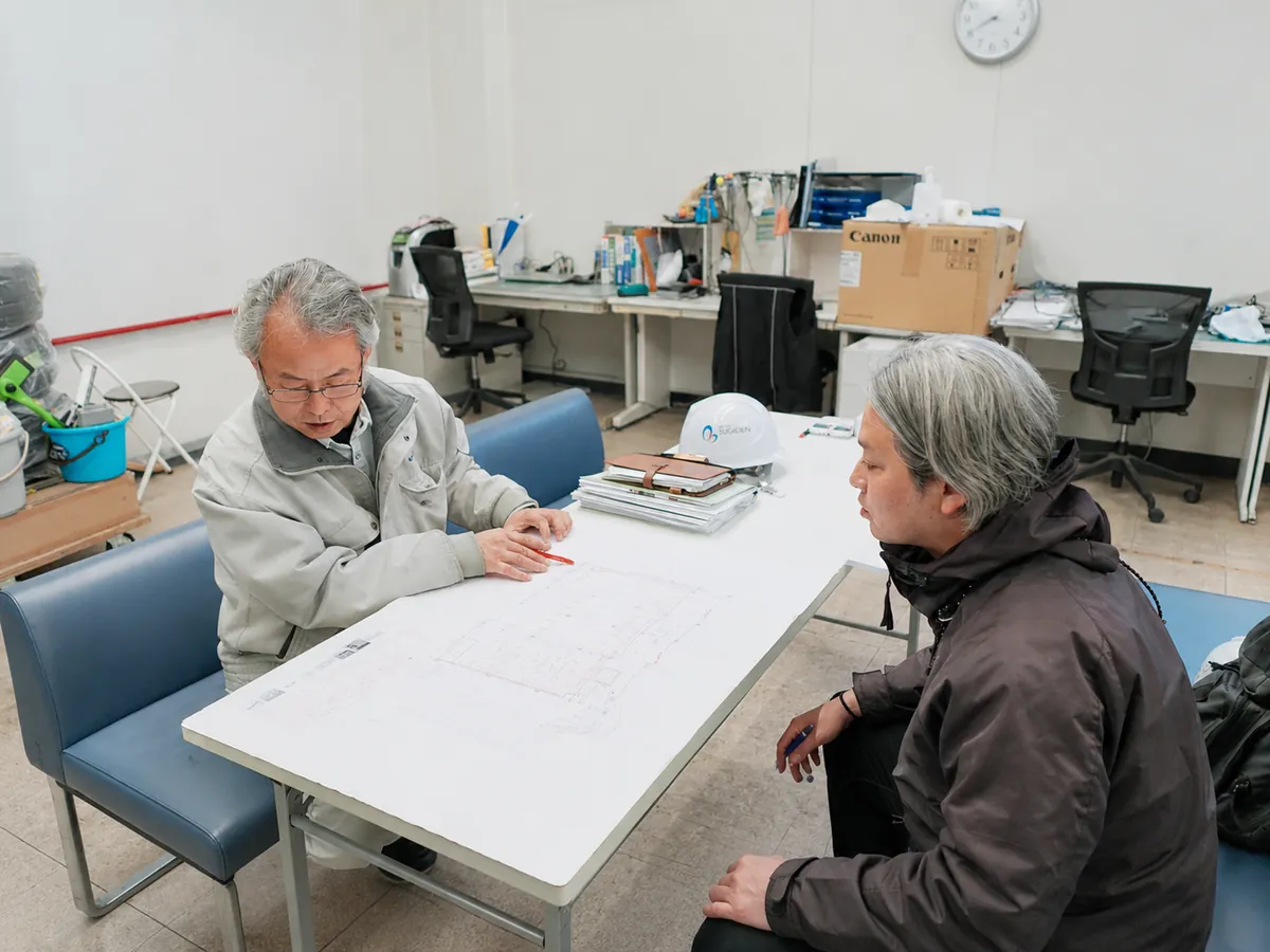 図面を挟んで現場担当者と会話する様子
